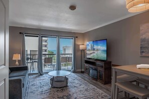 A hotel room with a balcony, a television, a sofa, a dining table, and a fireplace.