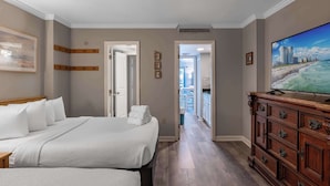 A hotel room with a large bed, a dresser, a television, and a view of the beach. - Ocean Dunes Tower II - Unit 6044 (Myrtle Beach)