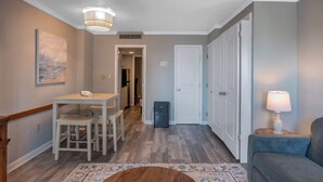 A hallway with a dining table, chairs, a lamp, and a couch. - Ocean Dunes Tower II - Unit 6044 (Myrtle Beach)