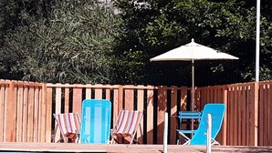 Une piscine avec des chaises bleues et un parasol blanc.