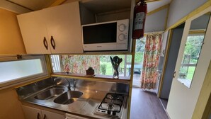 Une petite cuisine équipée d’un four à micro-ondes, d’un évier à deux bacs et d’une cuisinière à gaz.