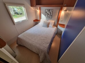 Un dormitorio con cama, ventana, lámpara de pared y un adorno decorativo.