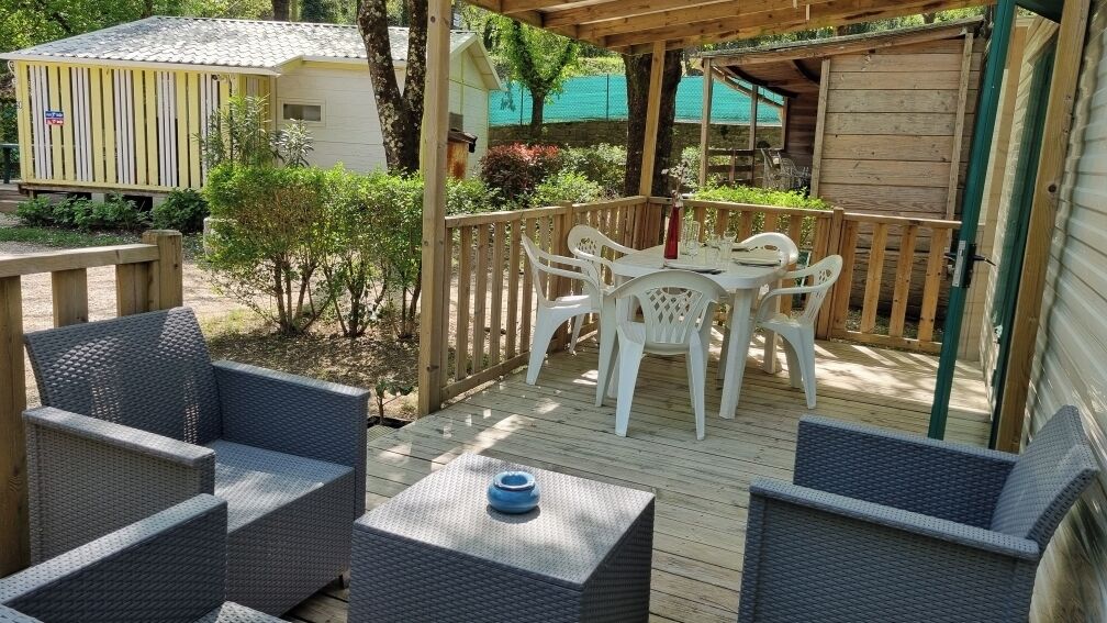 A covered outdoor patio with wicker furniture, a table, and a small blue object on the table.