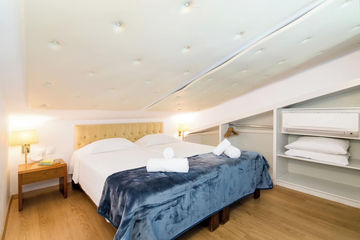 Ein Hotelzimmer mit Bett, Nachttischen, einem Kleiderschrank und einer Decke mit Einbauten.