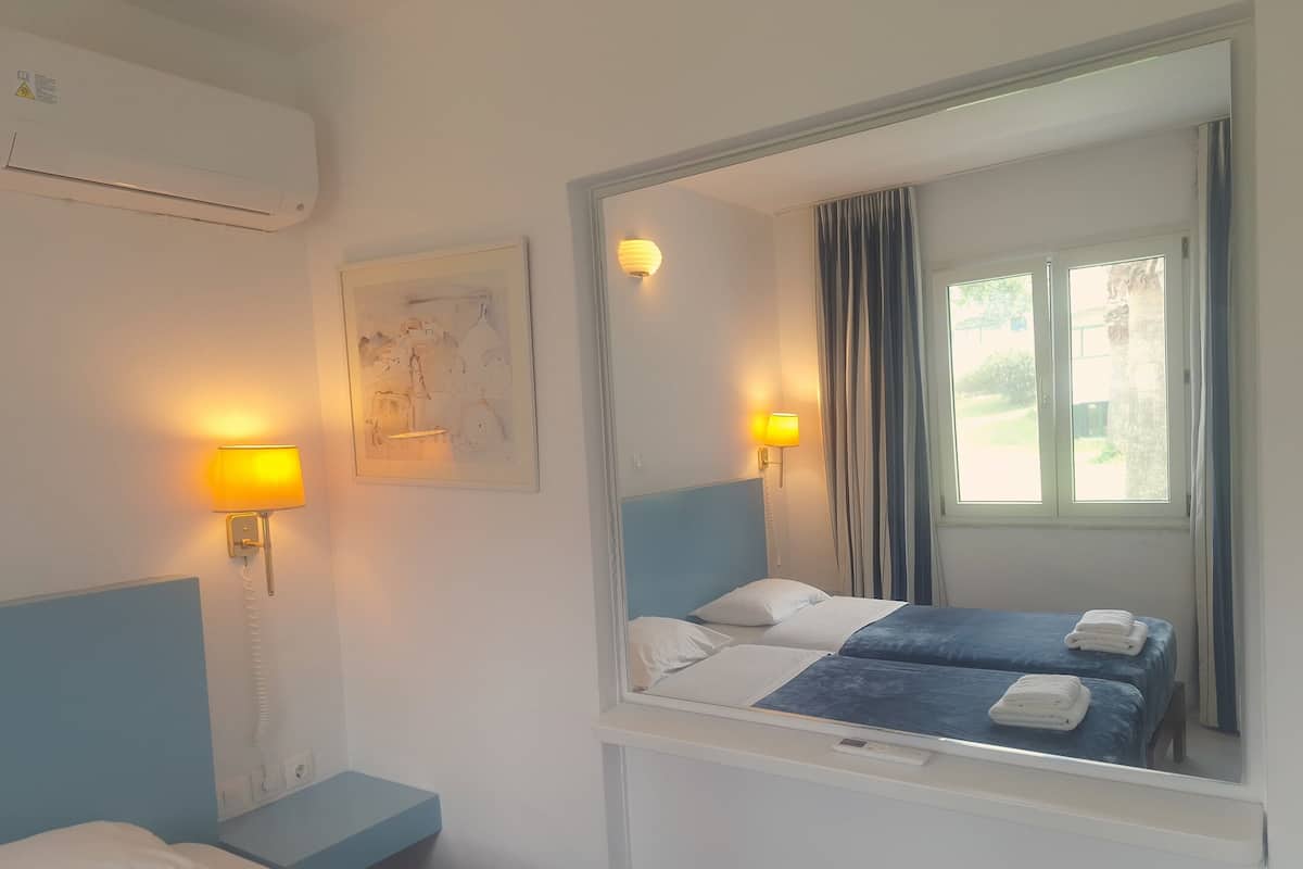 Ein Hotelzimmer mit einem Bett, Nachttischlampen, einem Spiegel und einem fenster mit Vorhängen.