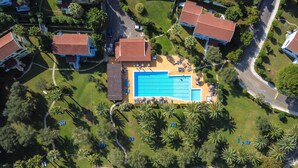 An aerial view of a resort with a central swimming pool, multiple villas, and a beachfront. - Helion Resort (Corfu)