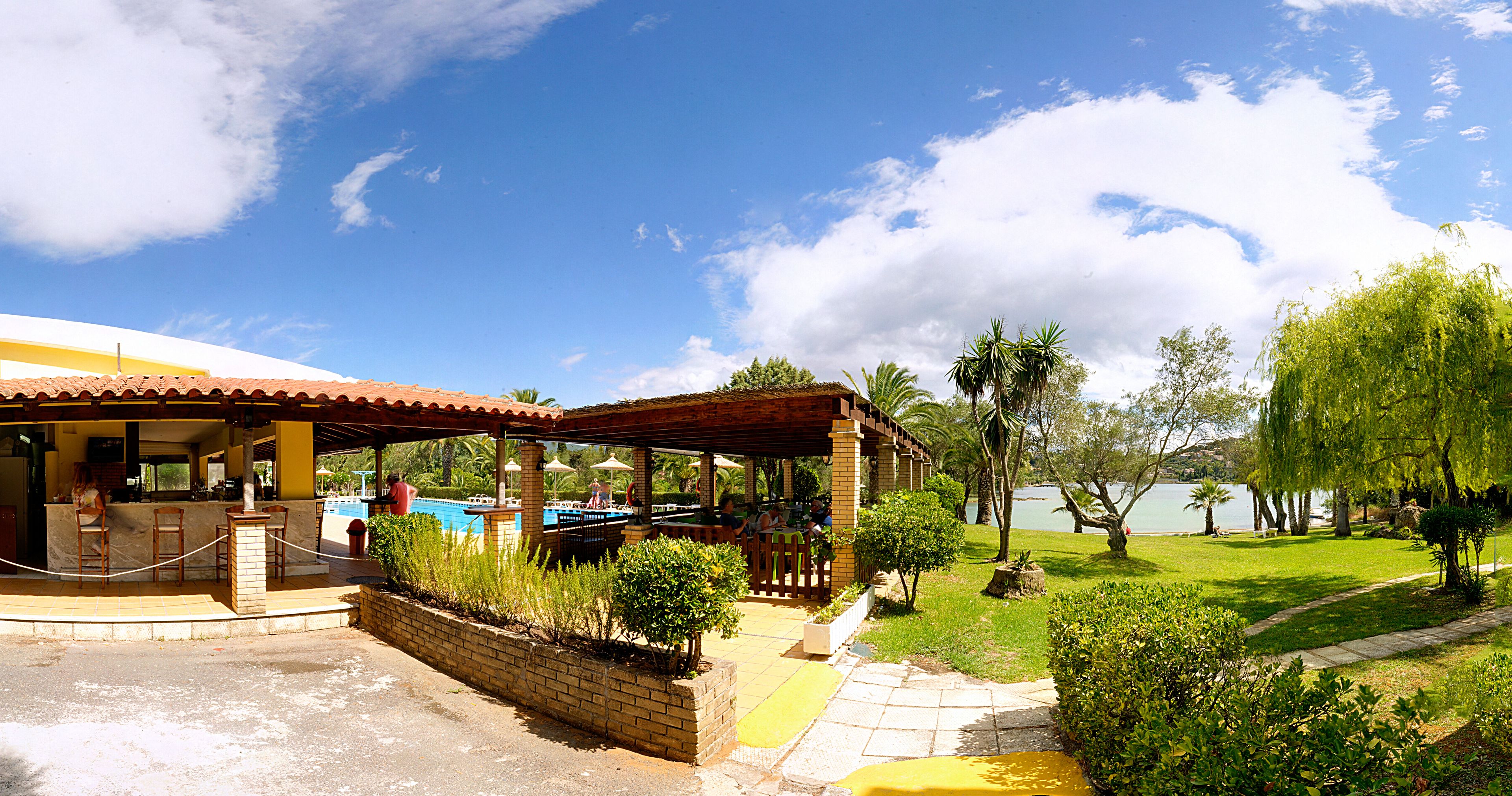 A covered outdoor area with a pool, seating, and a view of a lake.