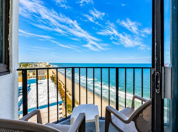A balcony with a view of the beach and ocean.