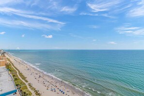 A beach with a clear sky, a sandy shore, and a view of the ocean.