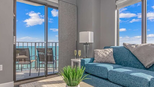 Een balkon met uitzicht op de oceaan, een blauwe bank, een witte lamp en een plant.