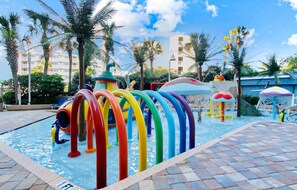 A swimming pool with colorful water slides and palm trees. - Coral Beach 816 LOP (Myrtle Beach)