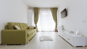 Una sala de estar moderna con un sofá verde, un aparador blanco y una alfombra de piel.