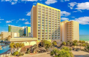 A hotel with multiple floors, a pool, and a view of the ocean.