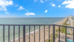 A coastal view from a balcony overlooking a beach with a clear sky. - Palace 1505 (Myrtle Beach)
