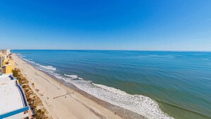 A beach with a clear view of the ocean and a row of buildings along the shore. - Palace 1505 (Myrtle Beach)