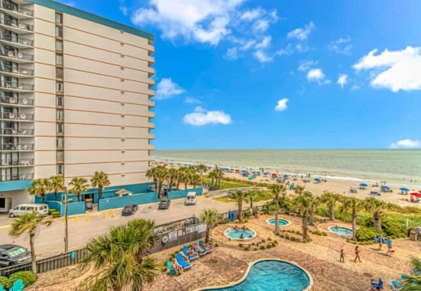 A hotel with a pool area, beach access, and a view of the ocean.