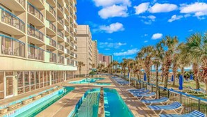Un hotel con piscina, tumbonas y palmeras.
