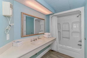 A bathroom with a white sink, mirror, and shower curtain.