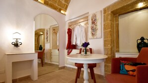 A dining area with a round table, chairs, and a wall-mounted lamp. - Relais la Casa del Poeta (Gallipoli)
