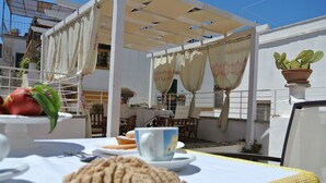 An outdoor dining area with a table set for two, featuring a plate of pastries, a cup, and a potted cactus. - Relais la Casa del Poeta (Gallipoli)