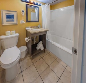 A bathroom with a toilet, sink, mirror, and shower curtain.