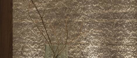 A window with a textured wall and a vase with branches.