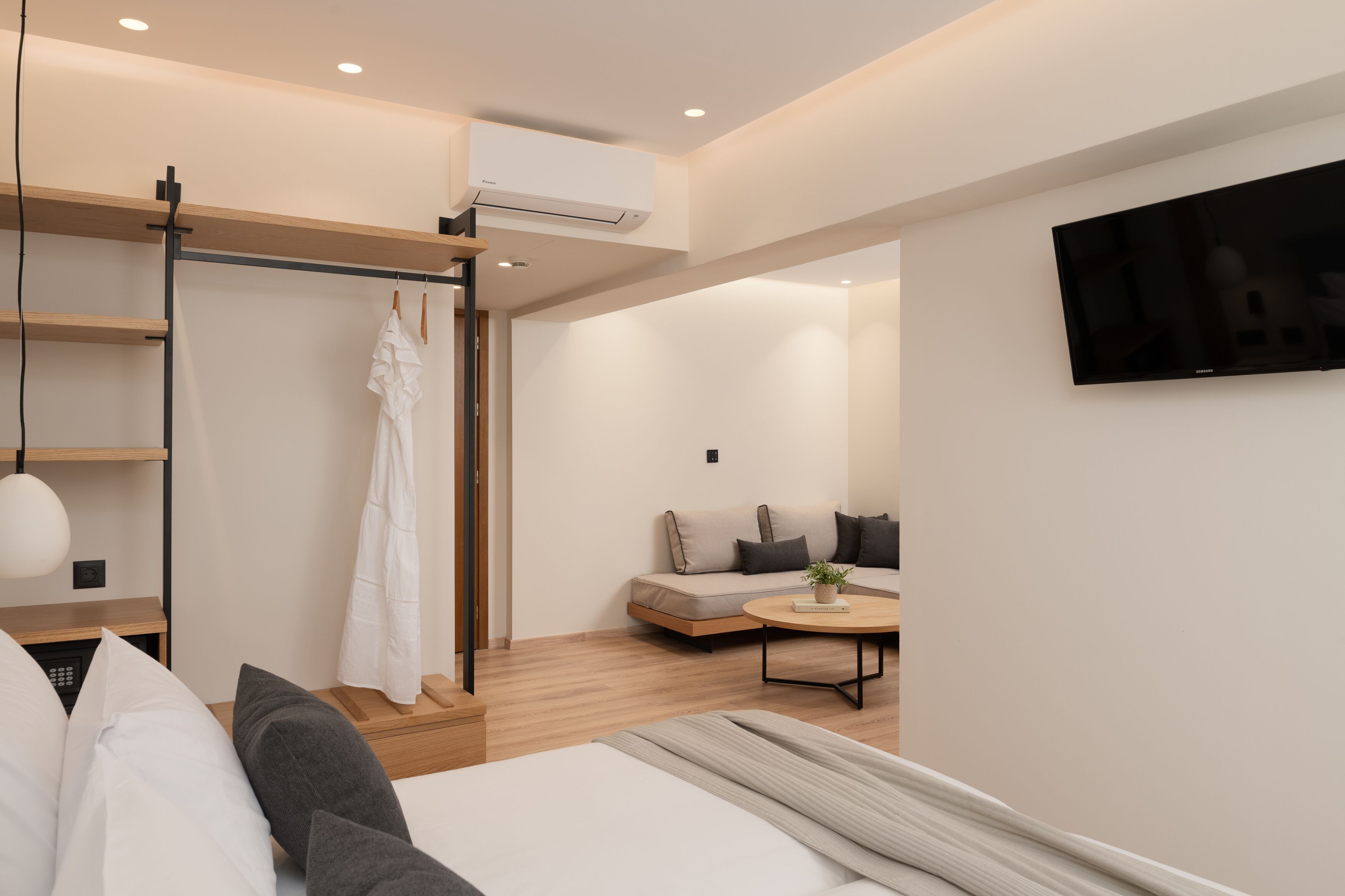A modern hotel room with a bed, bedside table, and a TV mounted on the wall.