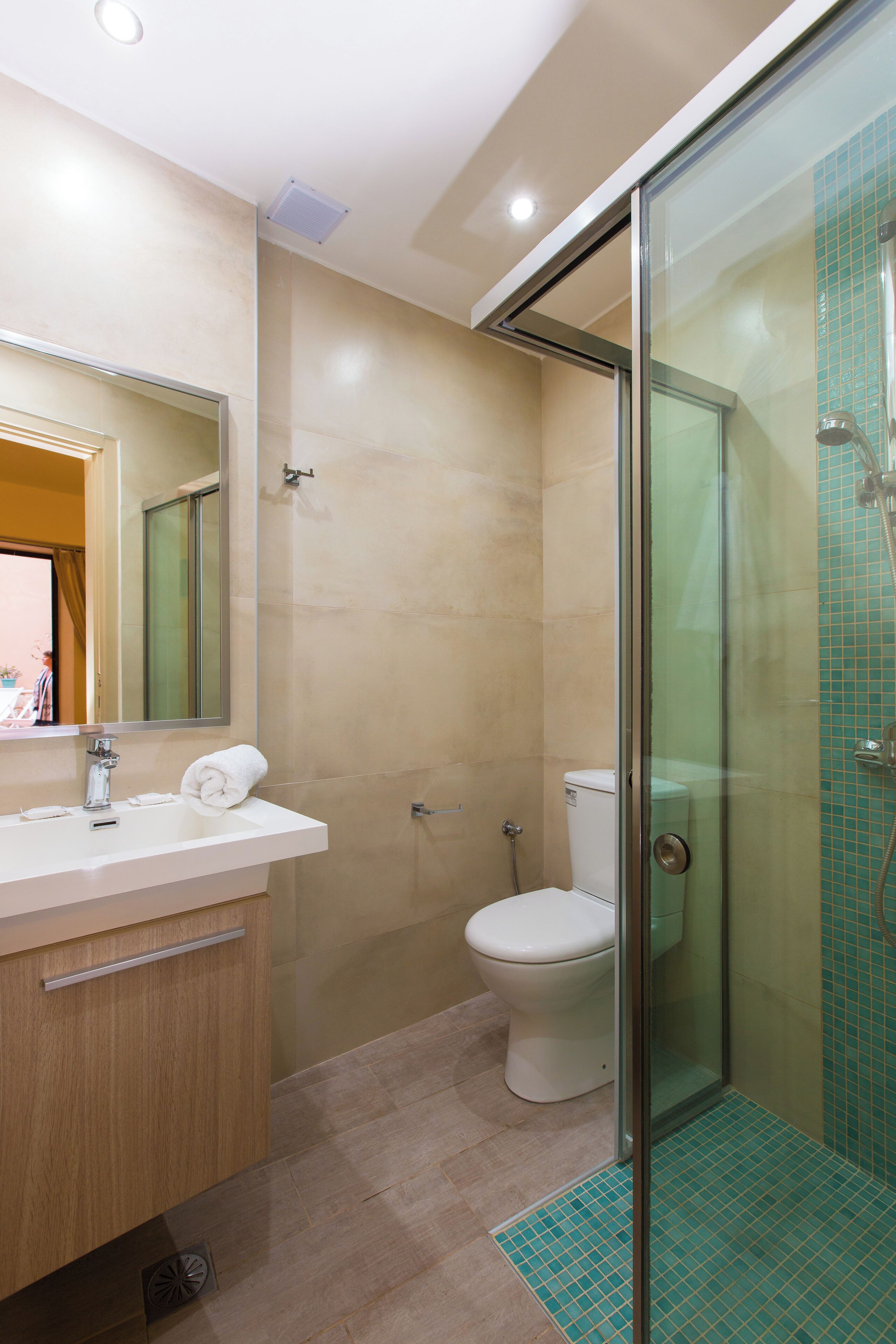 Un baño moderno con cabina de ducha de vidrio, un lavabo blanco y un inodoro.
