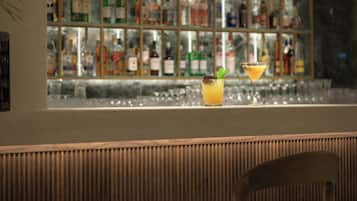 Baaritiski, jonka takana on lasivitriini täynnä pulloja, kaksi tuolia ja martini-lasi, jossa on sitruunaviipale koristeena.