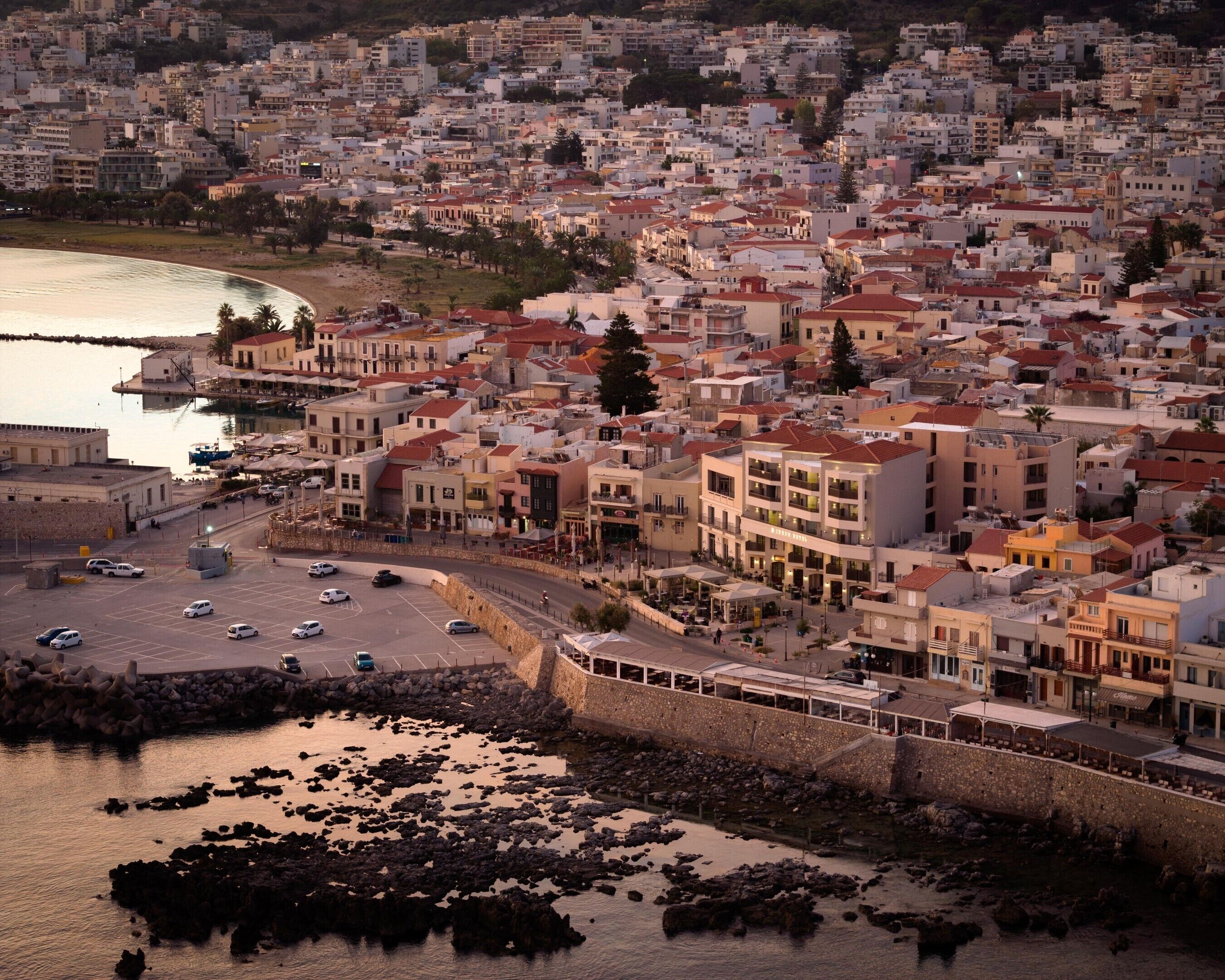 A coastal cityscape with a marina, buildings, and a stone wall.