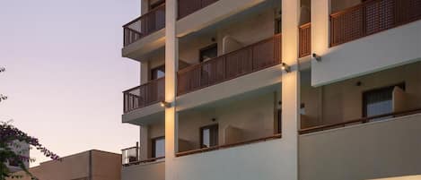 A multi-story hotel with balconies, a swimming pool, and outdoor seating.