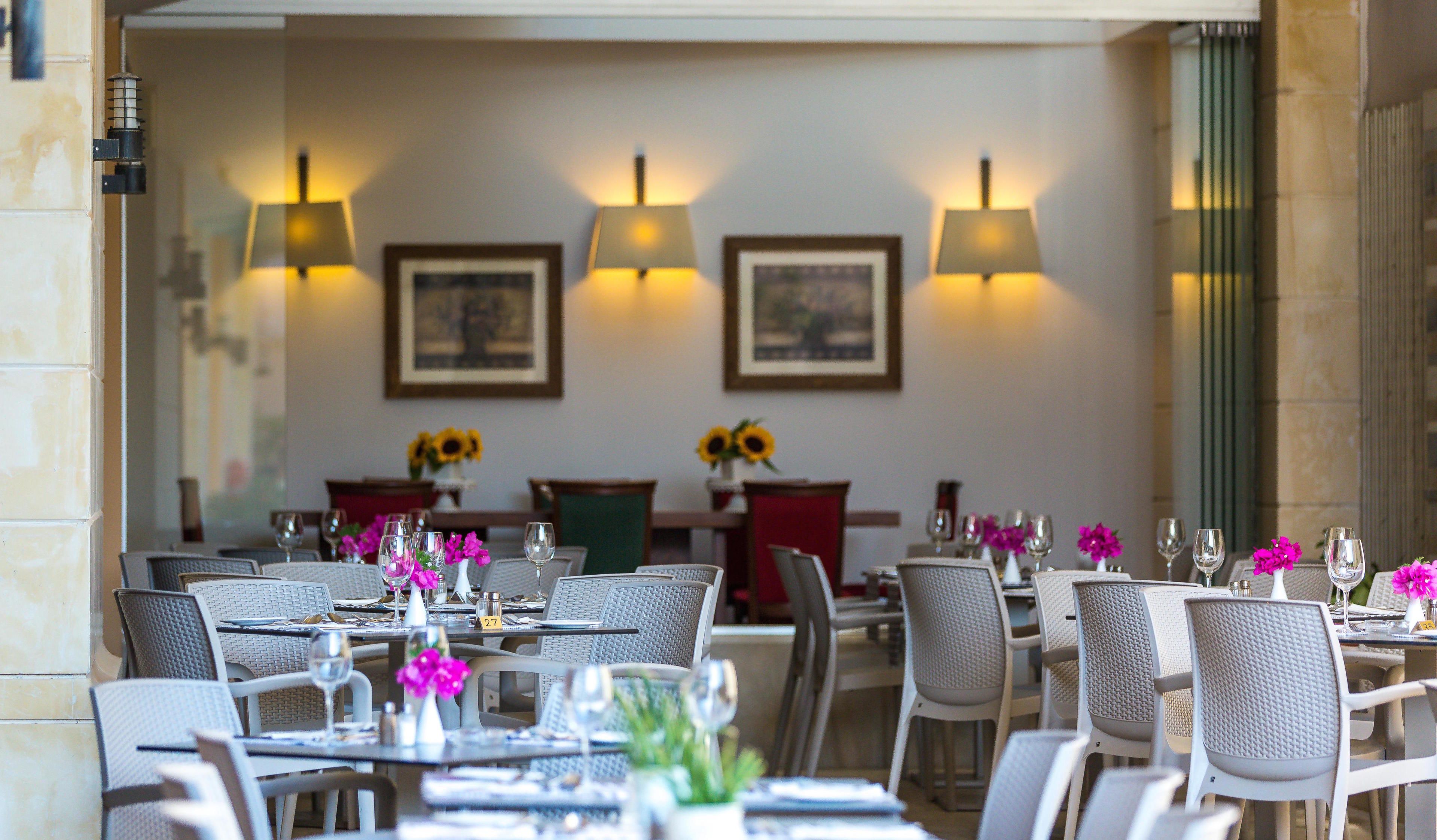 A restaurant with tables set for dining, chairs, and sunflowers on the tables.