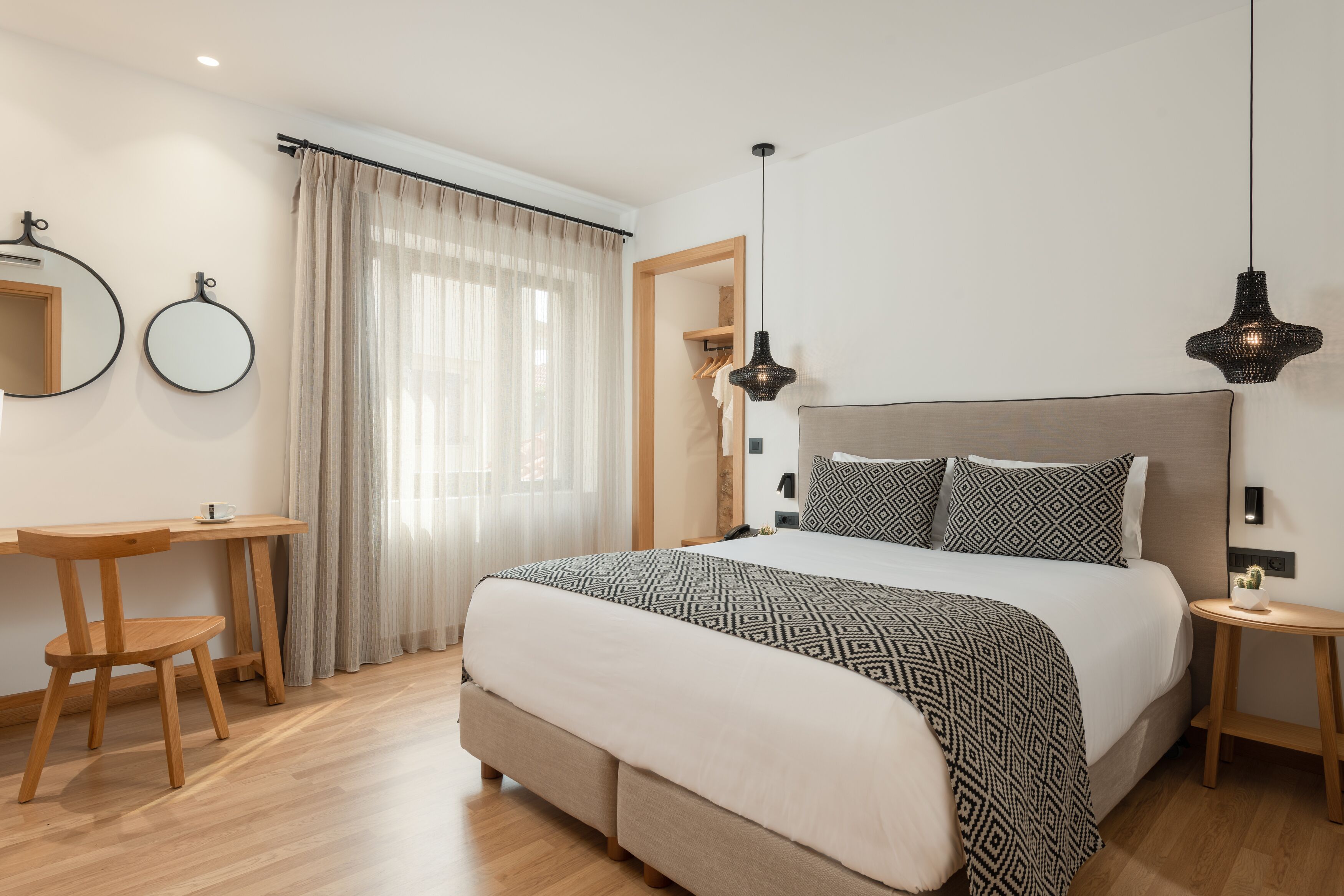 A bedroom with a bed, bedside tables, a desk, and a chair.