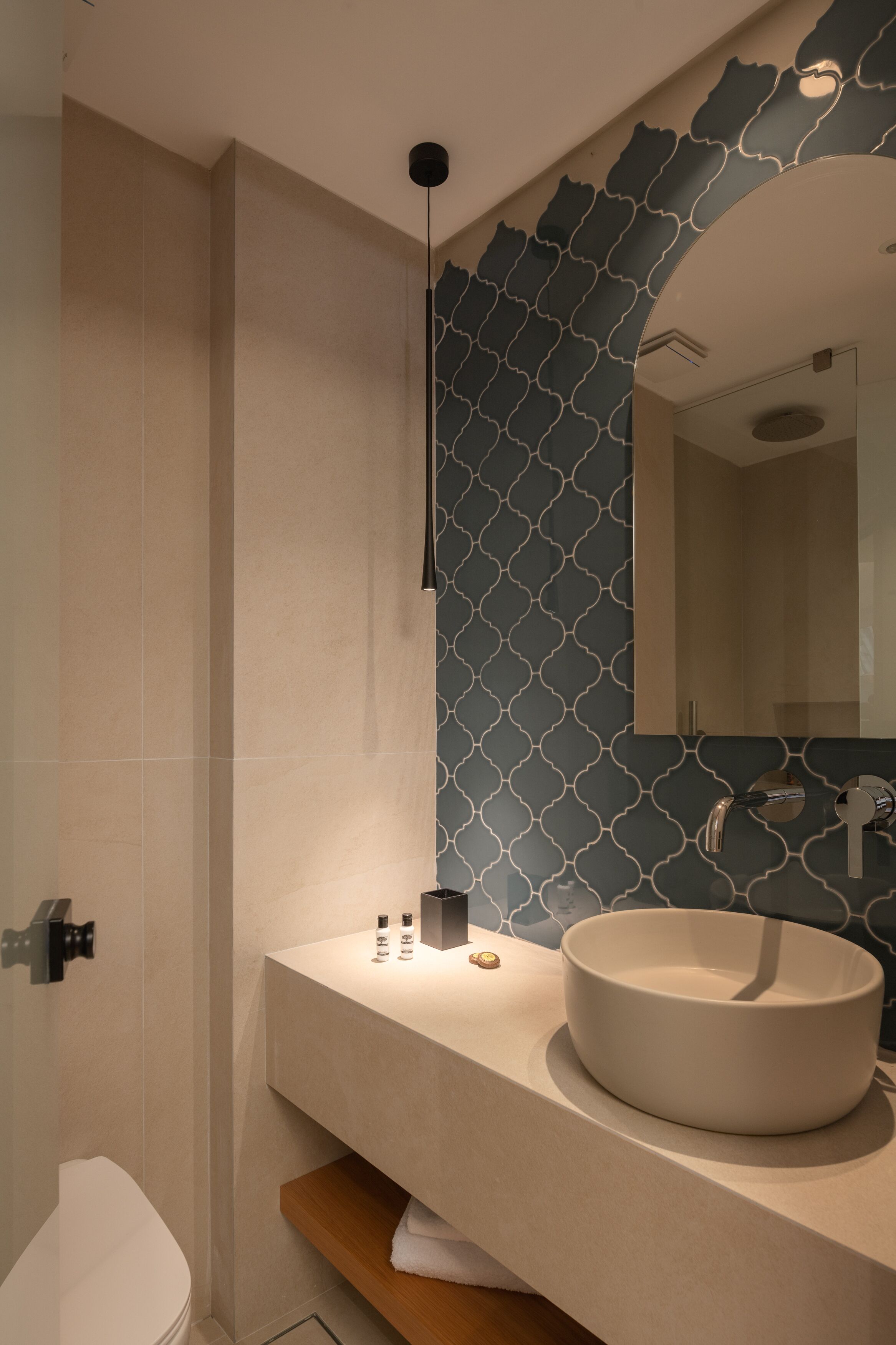 Ein modernes Badezimmer mit einem runden Waschbecken, einem Spiegel und einer Wand mit Muster.