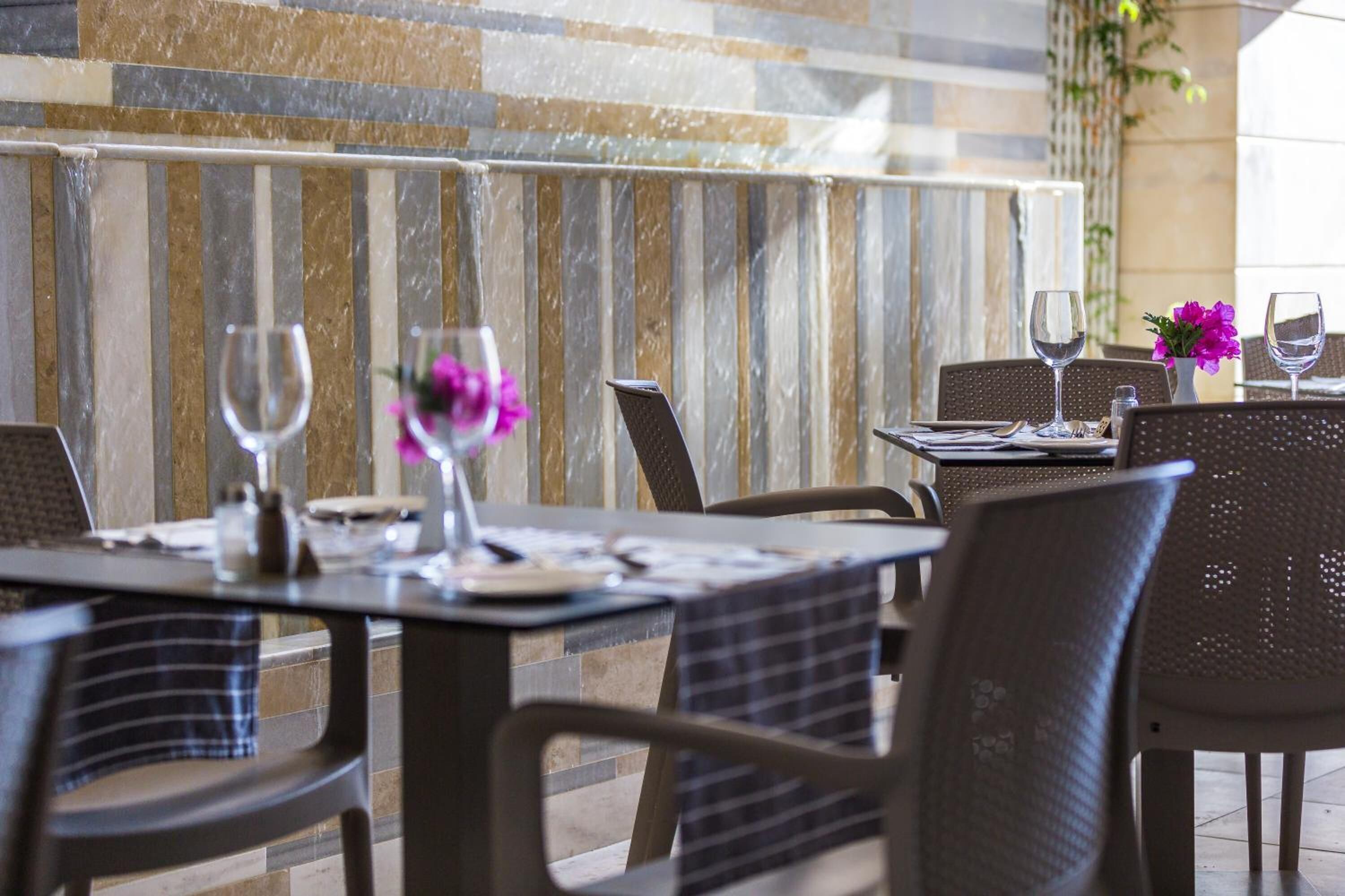 Un restaurante con terraza, paredes de piedra y vistas al cielo.