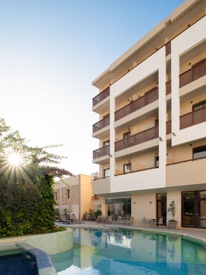 A modern hotel with a swimming pool, multiple balconies, and outdoor seating areas. - Hotel Ideon (Rethymno)