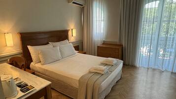 Habitación de hotel con cama, mesitas de noche, escritorio con tetera y cortinas.