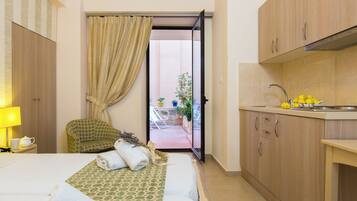 Habitación de hotel con cama, una silla, un pequeño balcón y kitchenette.