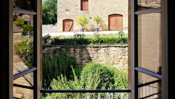 Un edificio de piedra con puertas y ventanas de madera, visto a través de un ventanal abierto.