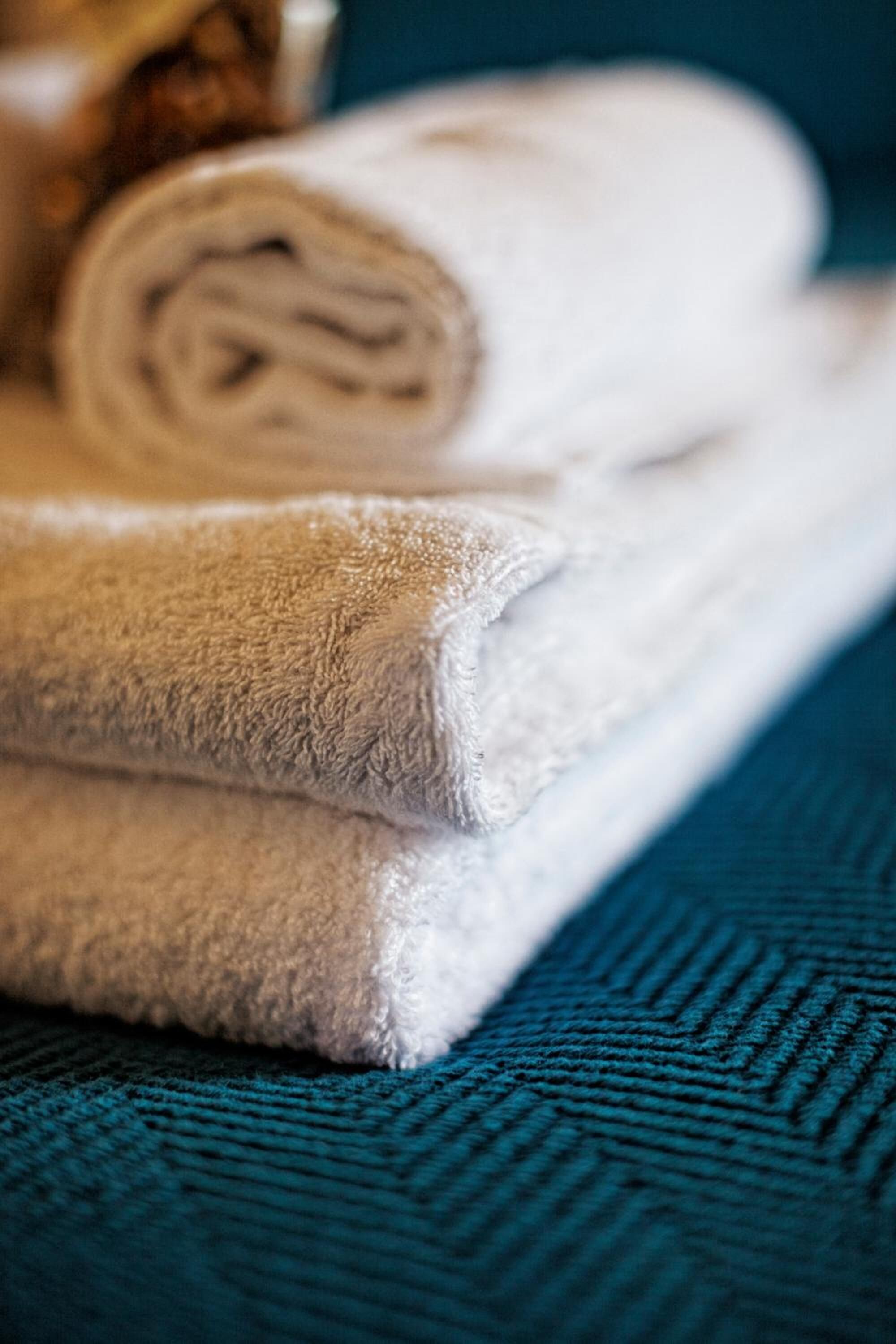 A stack of folded towels on a textured blue surface.