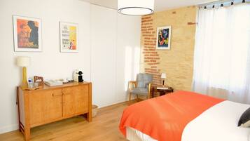 A bedroom with a bed, a wooden dresser, a chair, and two posters on the wall.