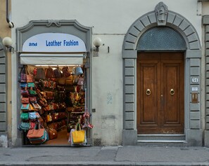 Une vitrine avec une enseigne indiquant « et articles de mode en cuir » et une variété de sacs à main exposés à l’extérieur.