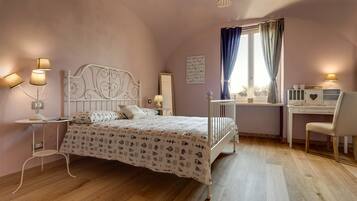 A bedroom with a bed, bedside tables, a desk, and a chair.