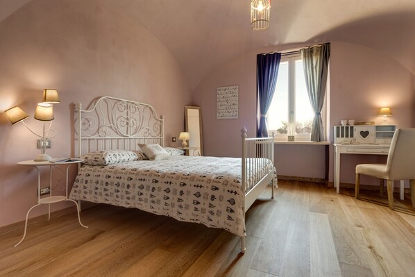 A bedroom with a bed, bedside tables, a desk, and a chair.