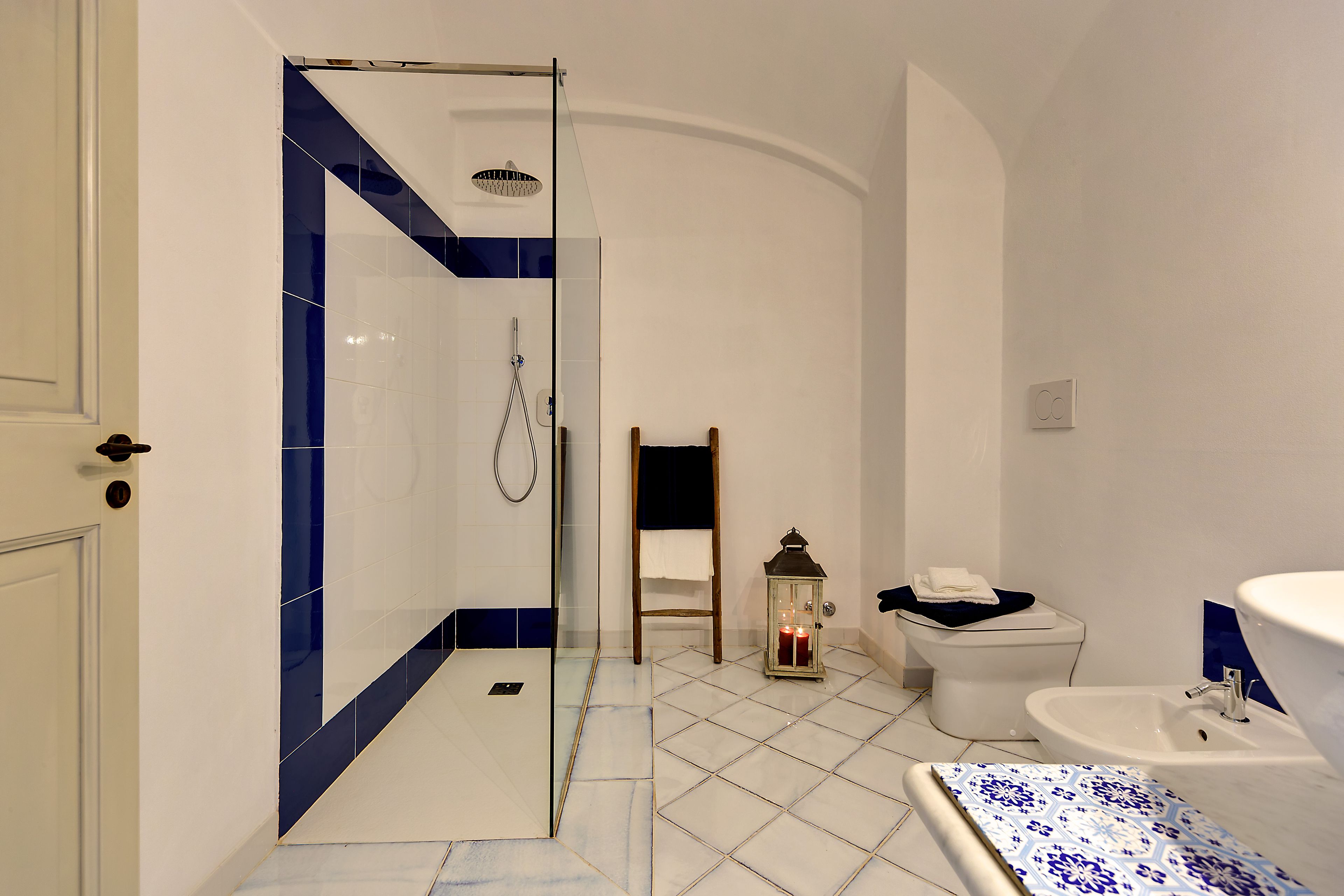 Ein Badezimmer mit Dusche, Toilette, Waschbecken und einer dekorativen Laterne.