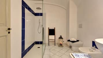 Ein Badezimmer mit Dusche, Toilette, Waschbecken und einer dekorativen Laterne.