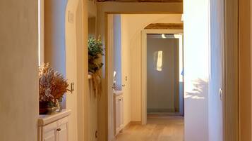 A hallway with a wooden floor, white walls, and a door at the end.