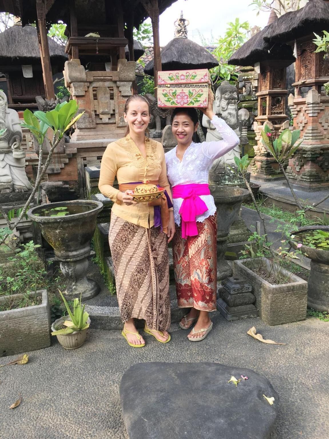 Two individuals standing in a courtyard with stone planters and traditional architecture.