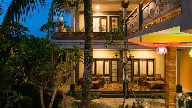 A two-story building with a balcony, a covered outdoor seating area, and a well-maintained garden. - Bulan Bali Homestay (Ubud)