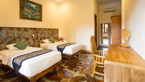 A hotel room with two beds, a wooden desk, and a patterned floor. - Bulan Bali Homestay (Ubud)